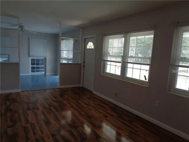 a view of an empty room with wooden floor and a window