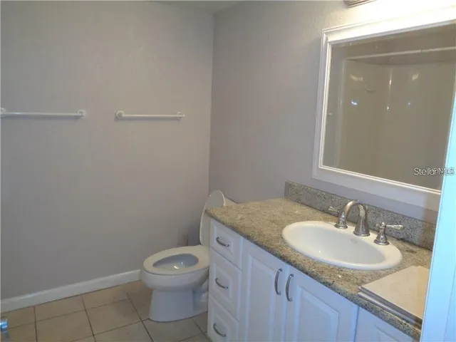 a bathroom with a granite countertop sink toilet and a mirror