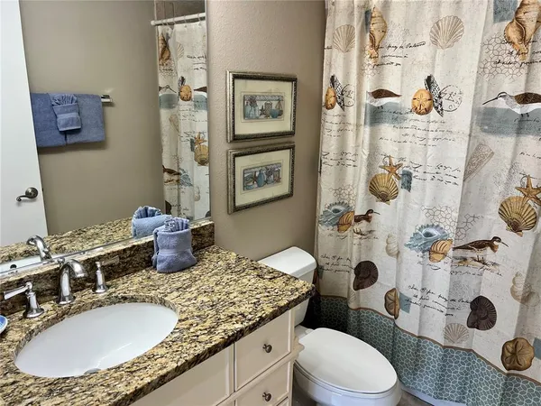 a bathroom with a granite countertop sink mirror vanity and toilet