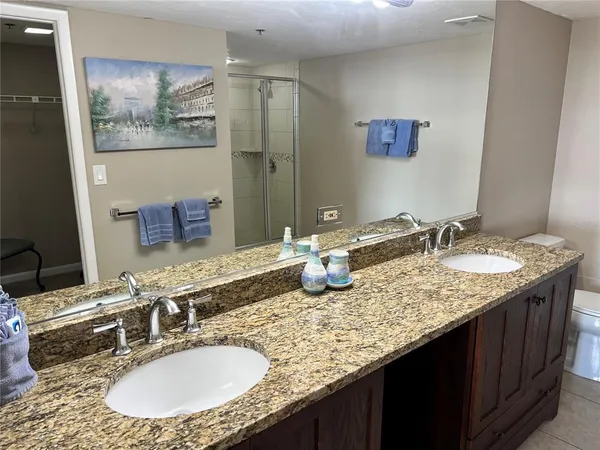 a bathroom with a granite countertop sink a mirror and a painting on the wall