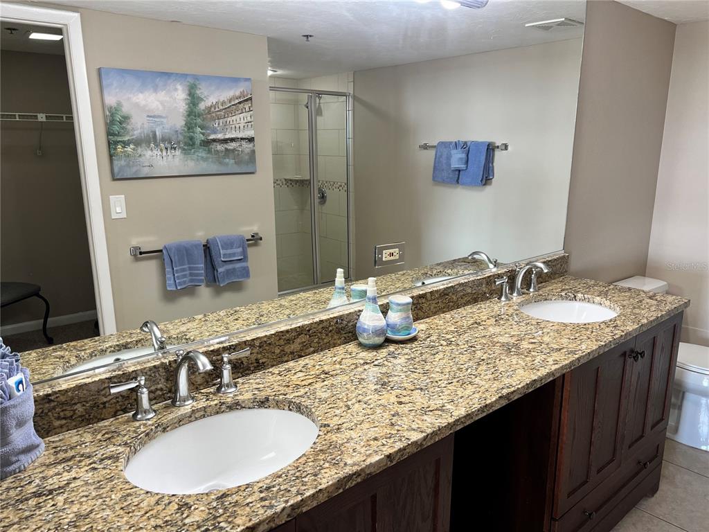1001 Point Of Rocks Road, Unit 608 Sarasota, FL 34242 - Photo 10 of 33 a bathroom with a granite countertop sink a mirror and a painting on the wall