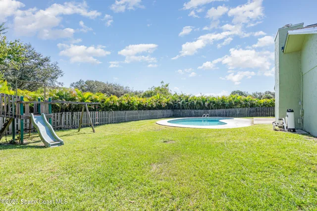 a view of a swimming pool with a yard and wooden fence