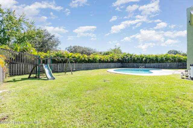 a view of a swimming pool with a patio and a yard