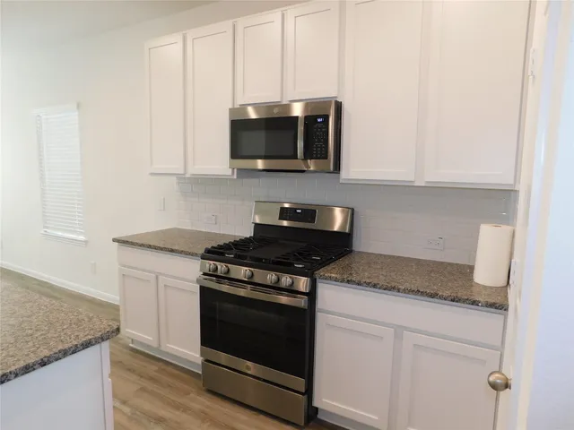 a kitchen with stainless steel appliances granite countertop white cabinets and a stove