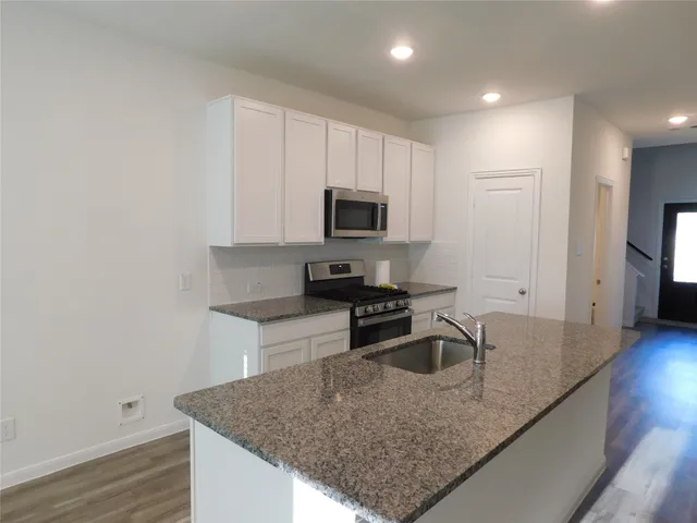 a kitchen with granite countertop a sink and a stove top oven with wooden floor