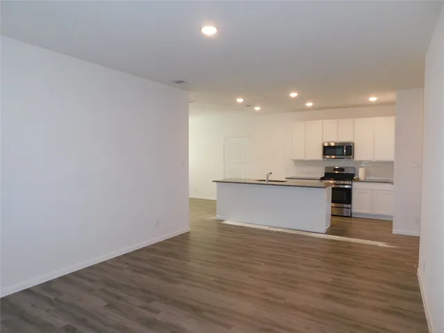 a view of kitchen with granite countertop cabinets and refrigerator