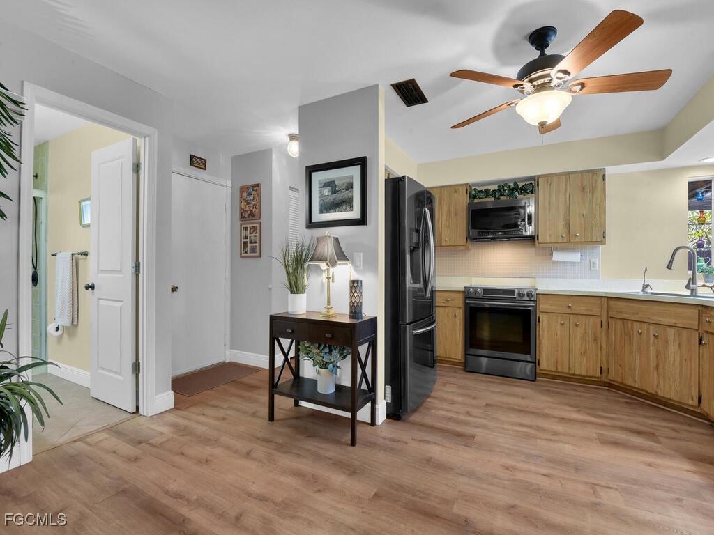 9041 Hamlin Road West Fort Myers, FL 33967 - Photo 8 of 34 a open kitchen with stainless steel appliances kitchen island granite countertop a stove top oven a sink a dining table and chairs with wooden floor