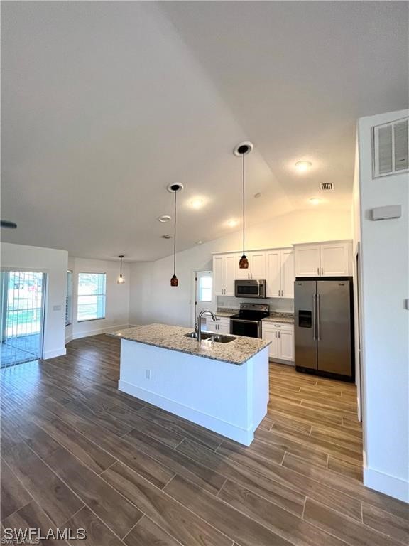 a kitchen with stainless steel appliances kitchen island granite countertop a refrigerator a oven and a wooden floors