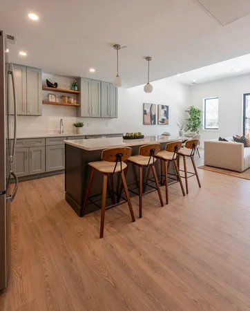 a open kitchen with stainless steel appliances granite countertop a stove a refrigerator a kitchen island a dining table and chairs with wooden floor