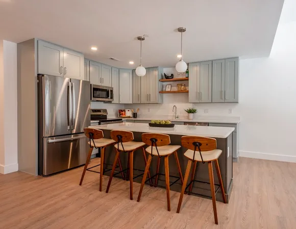 a kitchen with stainless steel appliances granite countertop a dining table chairs refrigerator and microwave