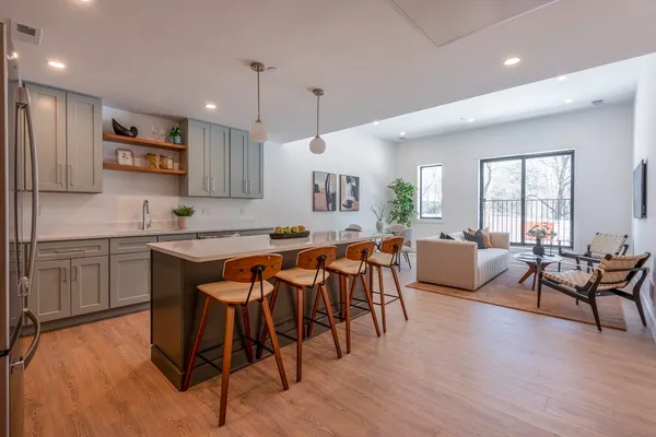 a open kitchen with stainless steel appliances granite countertop a stove a sink a microwave a dining table and chairs with wooden floor