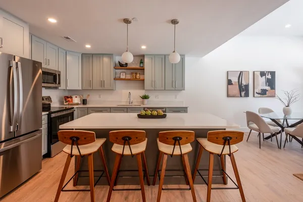 a kitchen with stainless steel appliances granite countertop a table chairs refrigerator and microwave