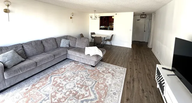 a living room with couches and a flat screen tv with kitchen view