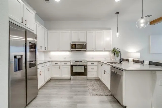 a kitchen with stainless steel appliances granite countertop a refrigerator a stove top oven a sink and dishwasher