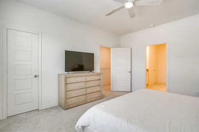 a bedroom with a large bed and a chandelier fan