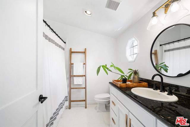 a bathroom with a granite countertop sink mirror vanity and toilet