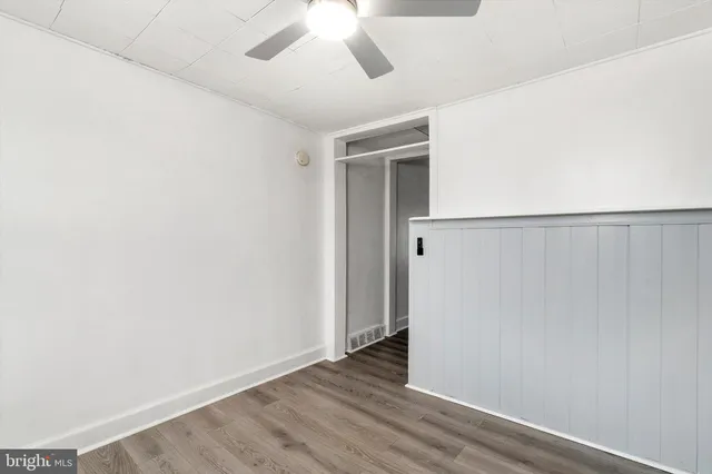 an empty room with wooden floor and fan