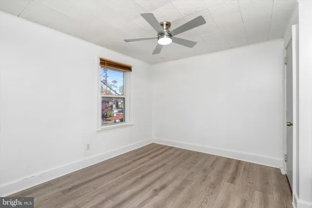 an empty room with wooden floor ceiling fan and windows