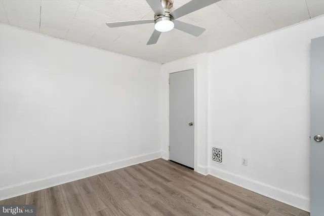 an empty room with a fan & a ceiling fan