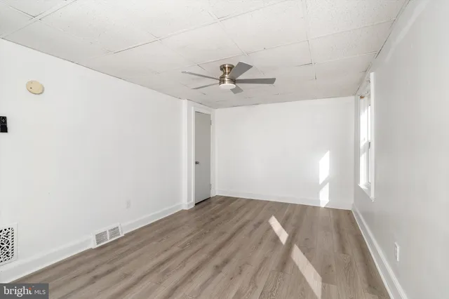 an empty room with wooden floor and chandelier fan