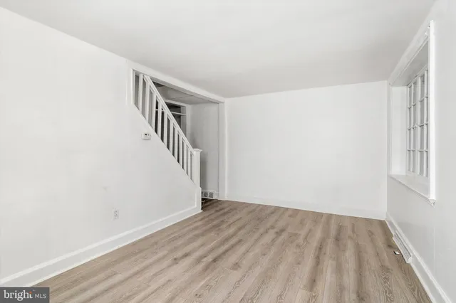 a view of an empty room with wooden floor and stairs