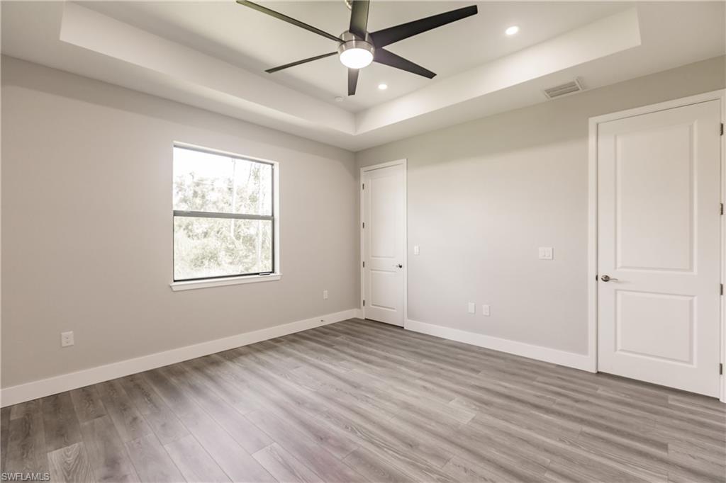 26395-26397 Explorer Road Punta Gorda, FL 33983 - Photo 10 of 18 an empty room with wooden floor chandelier fan and windows