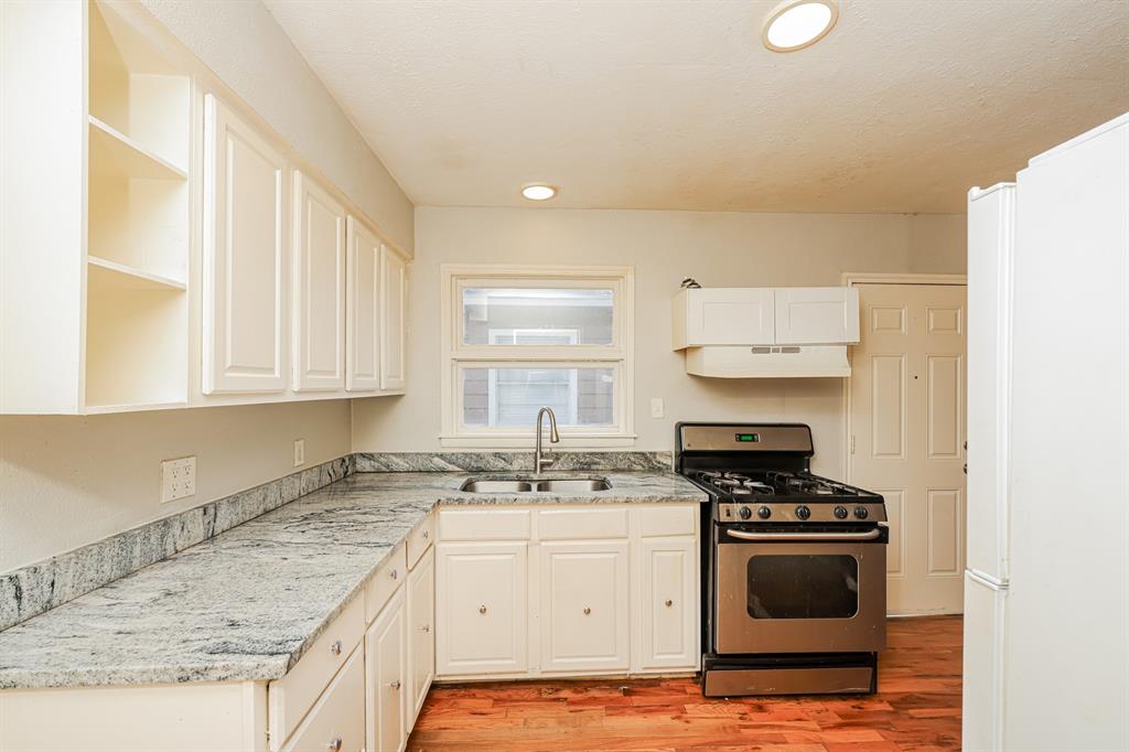 5175 Cardiff Street Dallas, TX 75241 - Photo 6 of 16 The kitchen features light-colored cabinetry, a stainless steel range, and a dual basin sink set into a patterned countertop
