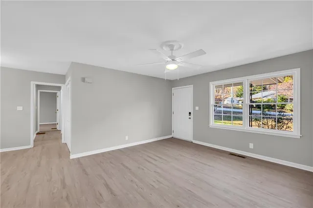 a view of an empty room with a window and wooden floor