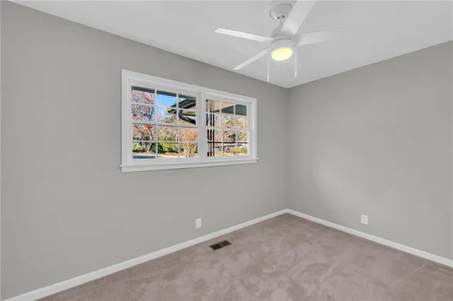 an empty room with a window and a ceiling fan