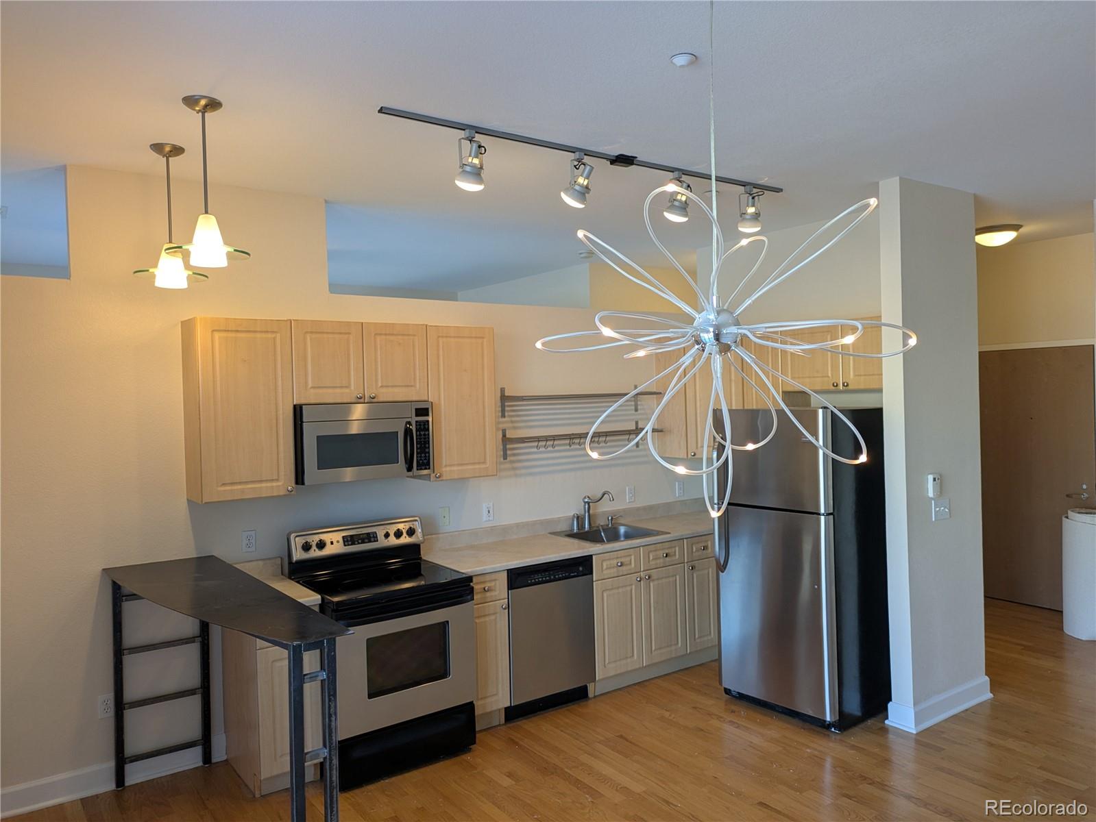 5677 South Park Place, Unit C204 Englewood, CO 80111 - Photo 6 of 13 a kitchen with stainless steel appliances a stove a refrigerator and a clock