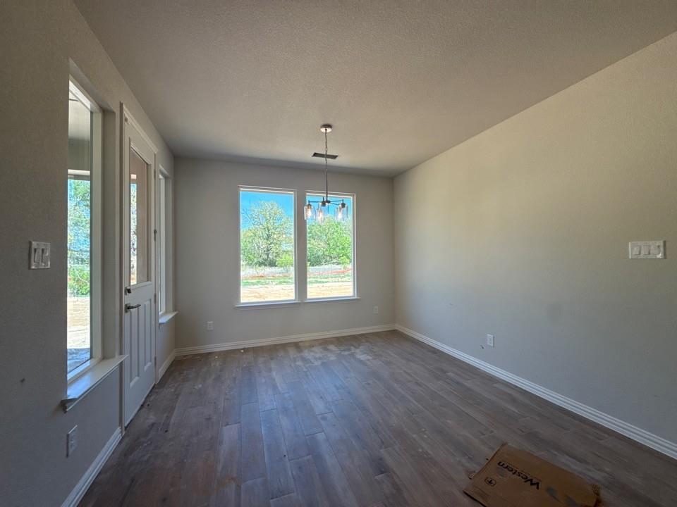 156 Oak Grv Way Springtown, TX 76082 - Photo 7 of 17 a view of an empty room with wooden floor and a window