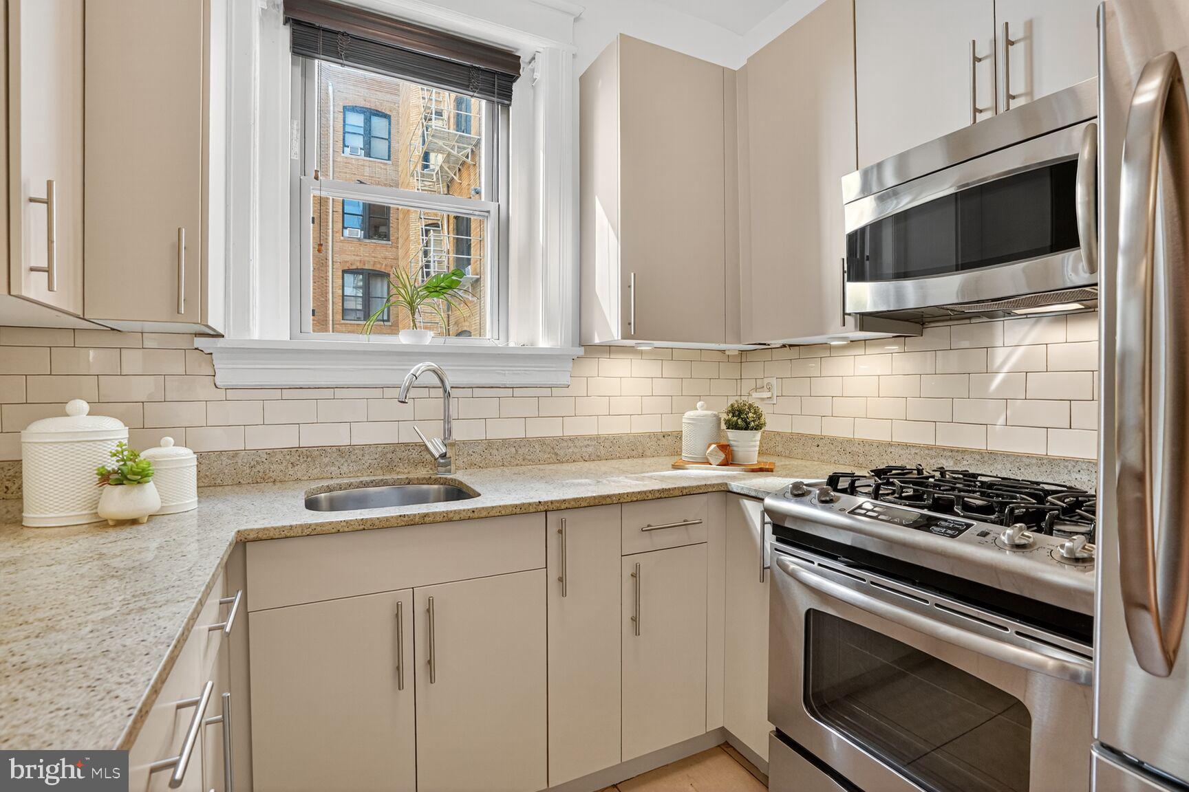 2010 Kalorama Road Northwest, Unit 506 Washington, DC 20009 - Photo 9 of 22 a kitchen with stainless steel appliances granite countertop a sink stove top oven and microwave