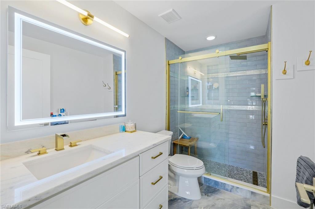 555 Augusta Boulevard, Unit 31 Naples, FL 34113 - Photo 11 of 17 a bathroom with a sink a toilet a shower and a mirror