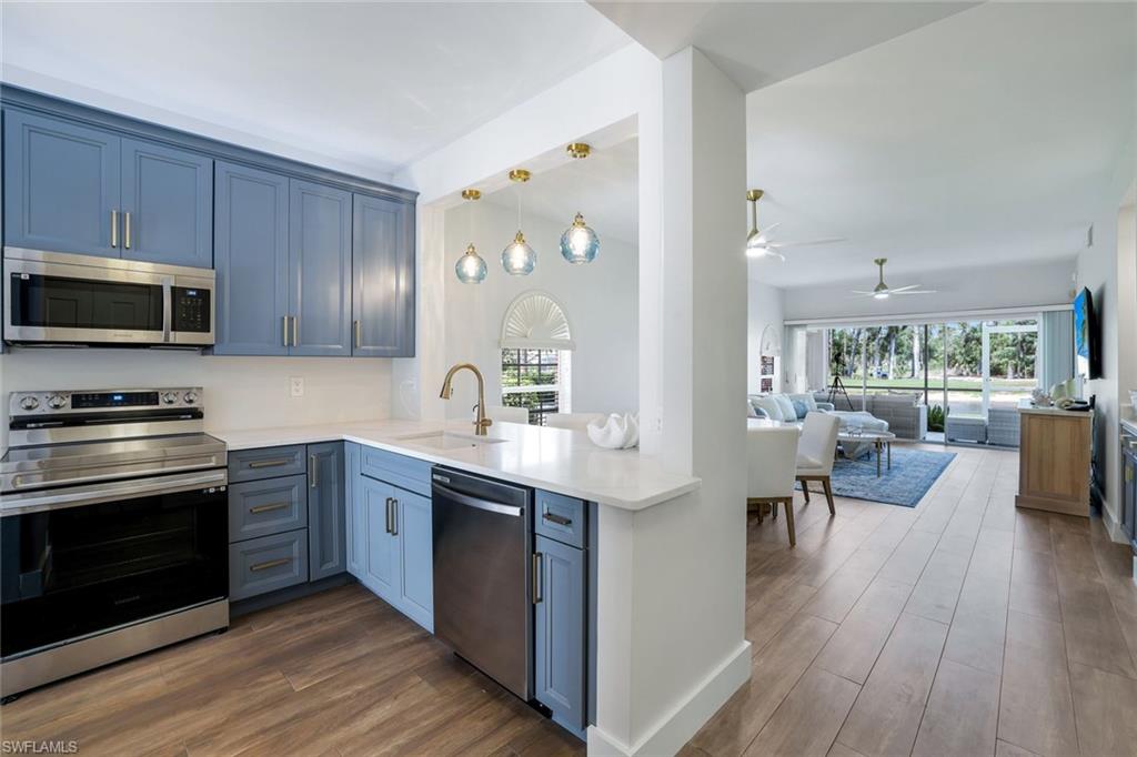 555 Augusta Boulevard, Unit 31 Naples, FL 34113 - Photo 6 of 17 a kitchen with stainless steel appliances a stove a sink cabinets and a wooden floor