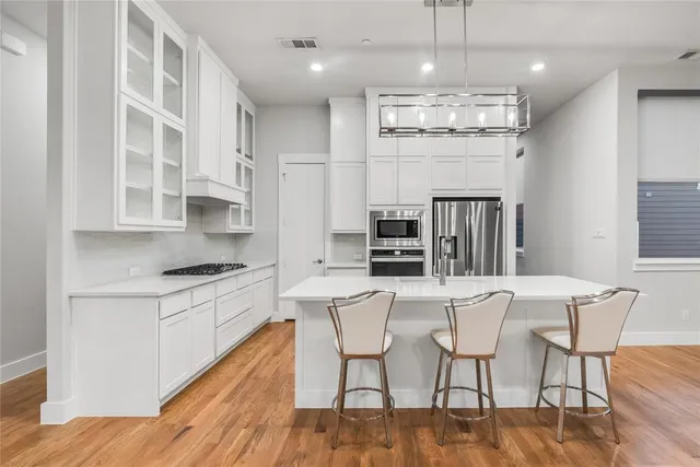 a kitchen with stainless steel appliances a dining table chairs stove and refrigerator