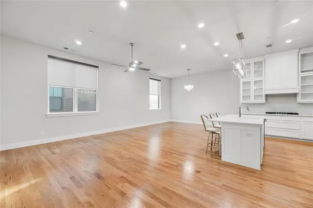 a kitchen with stainless steel appliances granite countertop a stove top oven a sink dishwasher and white cabinets with wooden floor