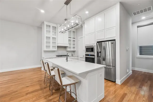 a kitchen with stainless steel appliances a dining table chairs refrigerator and microwave