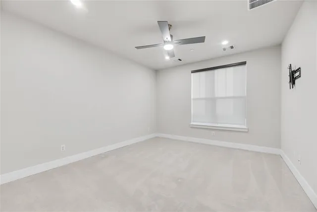 an empty room with a window and ceiling fan
