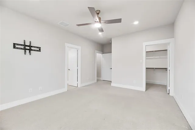 an empty room with closet and a ceiling fan