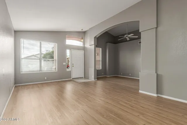 an empty room with wooden floor and windows