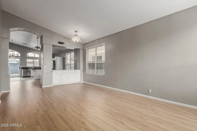 a view of an empty room with wooden floor and a large window