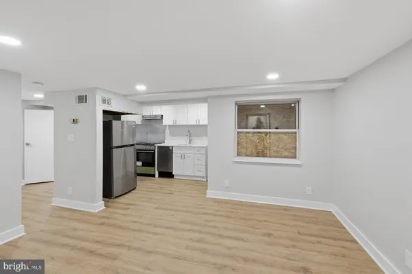 a view of a kitchen with a refrigerator wooden floor and a window