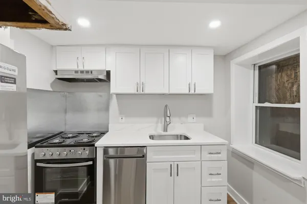 a kitchen with stainless steel appliances granite countertop a stove and a white cabinets