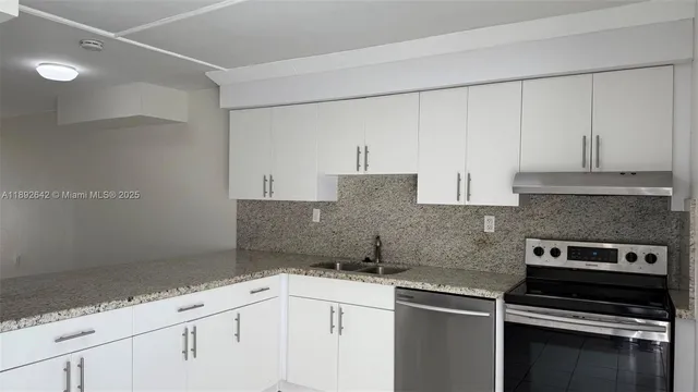 a kitchen with granite countertop white cabinets and stainless steel appliances
