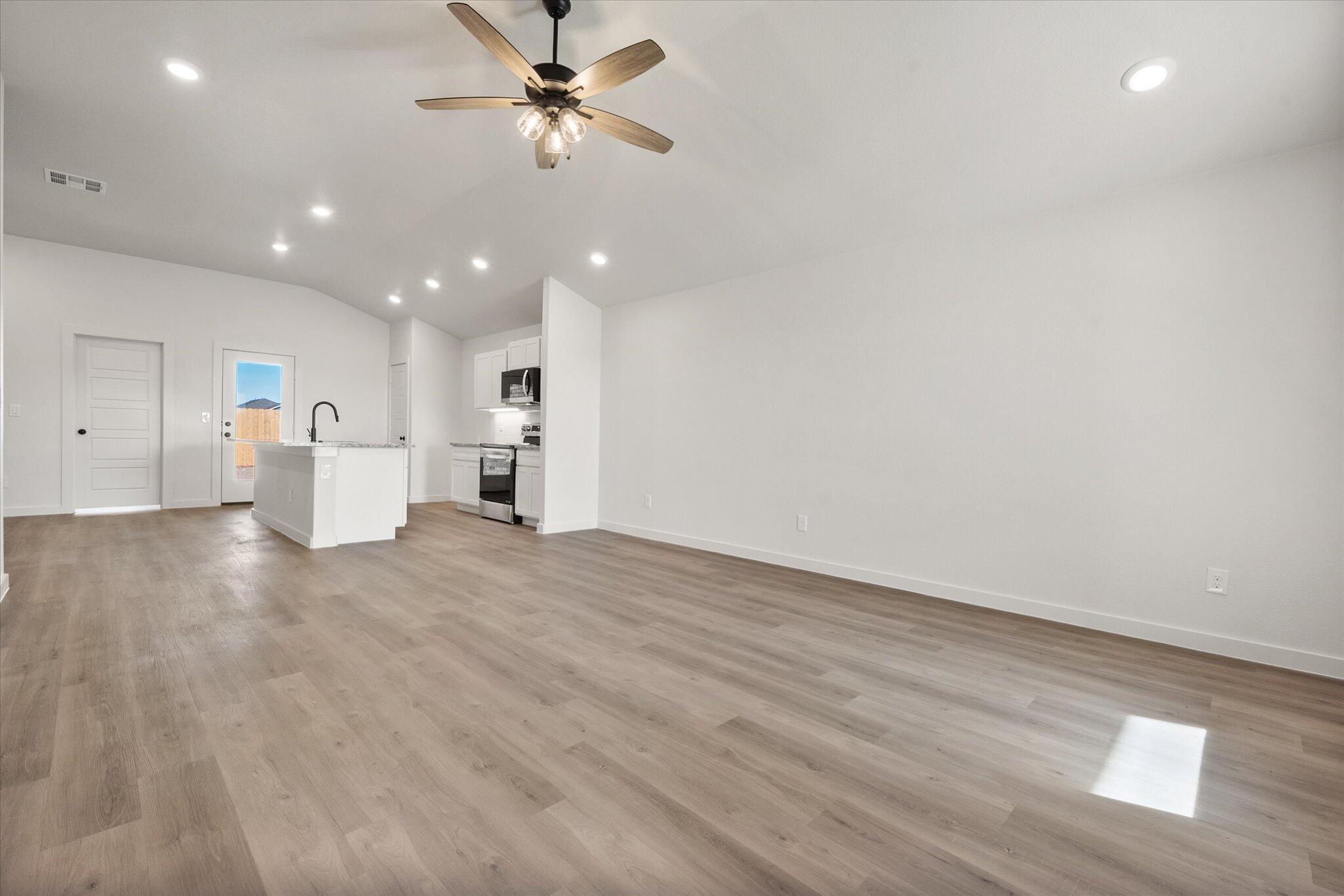 3108 138th Place Lubbock, TX 79423 - Photo 3 of 21 a view of an empty room and a kitchen with a ceiling fan window