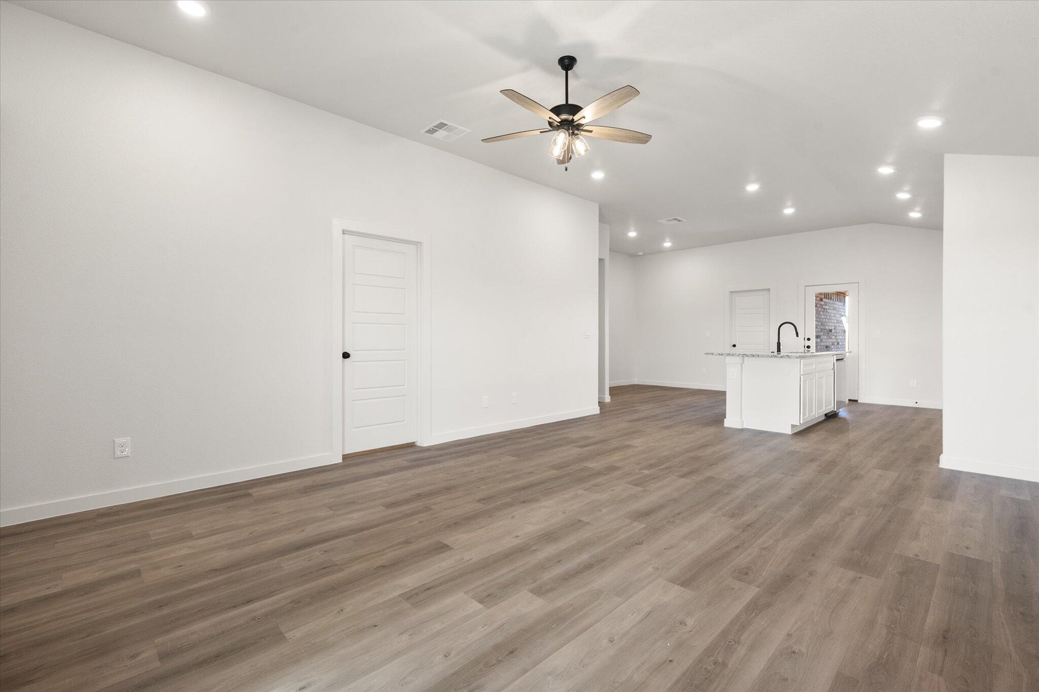 3108 138th Place Lubbock, TX 79423 - Photo 4 of 21 a view of an empty room with wooden floor and a ceiling fan