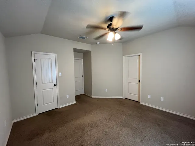 a view of an empty room and chandelier fan