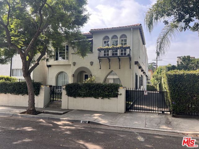a view of a white house with large tree and wooden fence