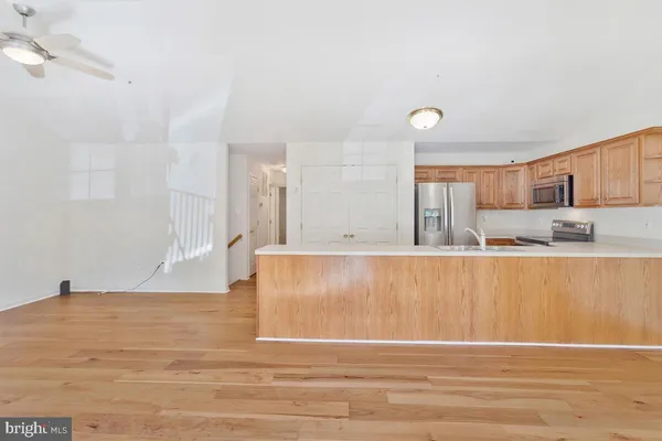 a view of a kitchen with kitchen island a sink wooden floor and a refrigerator