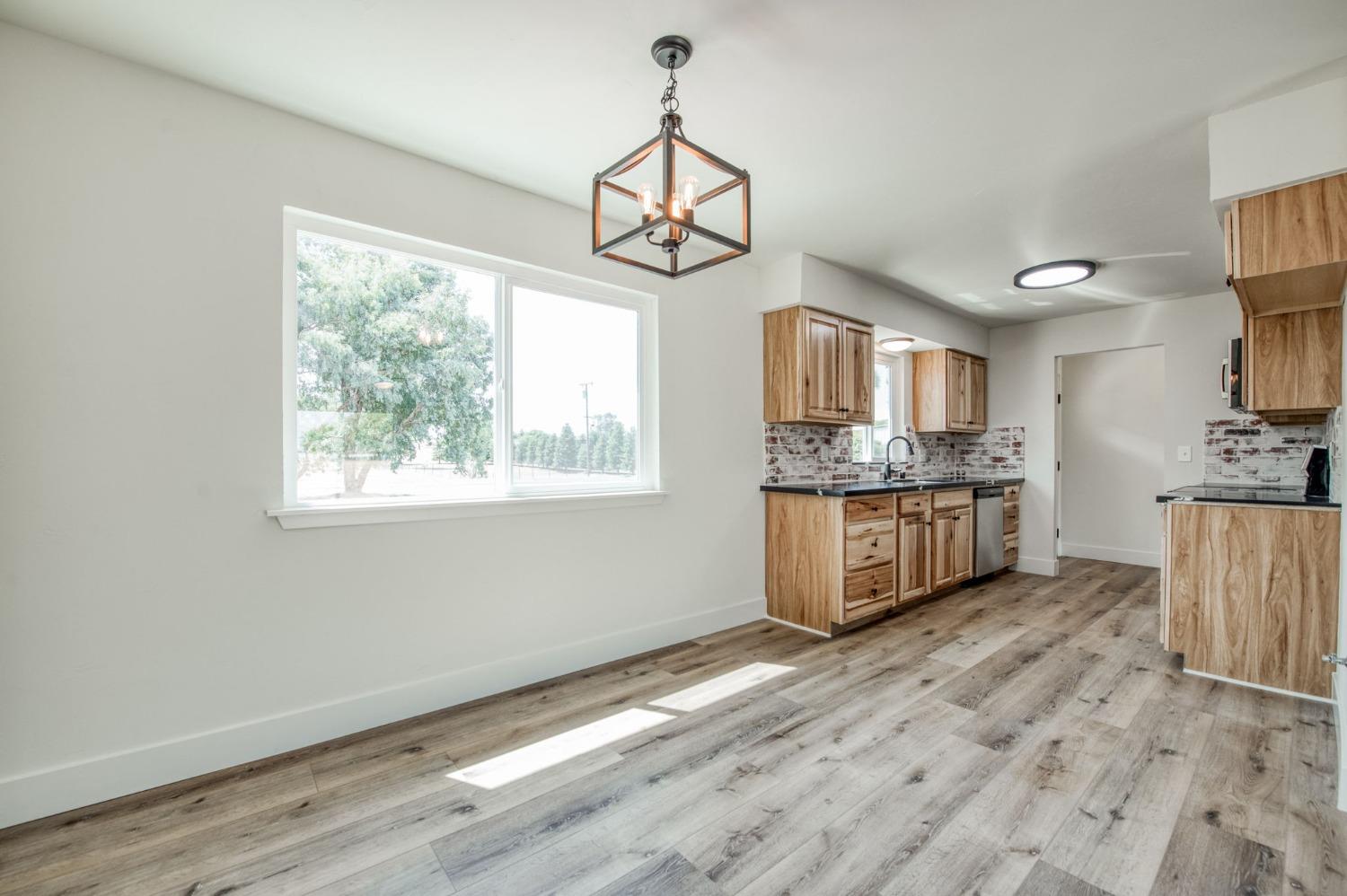 16715 Monreal Road Madera, CA 93636 - Photo 12 of 39 a kitchen with stainless steel appliances granite countertop a stove a sink and a wooden floors